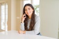 Young woman talking on the phone having a conversation with a happy face standing and smiling with a confident smile showing teeth Royalty Free Stock Photo