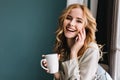 Young woman talking phone and laughing with cup of coffee, tea in hand, happy morning. She has beautiful wavy blonde Royalty Free Stock Photo