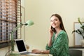 Young woman talking on phone while using laptop at table. Space for text Royalty Free Stock Photo