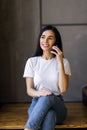 Young woman talking on the phone and working on a laptop on her lap while sitting on the stairs at home Royalty Free Stock Photo