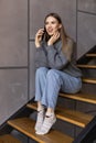 young woman talking on the phone and working on a laptop on her lap while sitting on the stairs at home Royalty Free Stock Photo