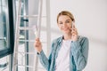 Young woman talking on smartphone while holding pink paintbrush and smiling at camera Royalty Free Stock Photo