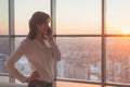 Young woman talking using cell phone at office in the evening. Female businesswoman concentrated, looking forward