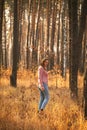 Young woman among tall pines in a wild forest. wilderness trip theme. Autumn in the woods Royalty Free Stock Photo