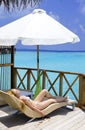 Young woman tans on villa on ocean Maldives Royalty Free Stock Photo