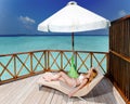 Young woman tans on a water villa terrace Royalty Free Stock Photo