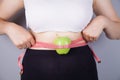 Young woman, tape measure and green apple