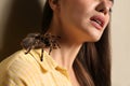 Young woman with tarantula on beige background. Arachnophobia fear of spiders