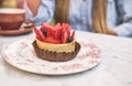 Young woman tasting strawberry-topped cake, Selective focus. Royalty Free Stock Photo