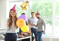 Young woman with tasty muffin and air balloons at birthday party in office Royalty Free Stock Photo