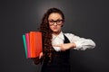 Young woman teacher in glasses pointing at pile of books Royalty Free Stock Photo