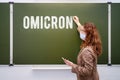 Young woman teacher with a phone in hand writes the text new variant of the coronavirus Omicron. Concept of problems at school Royalty Free Stock Photo
