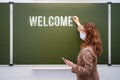 Young woman teacher with a phone in hand writes the text welcome back to school. Concept of problems at school during the Royalty Free Stock Photo