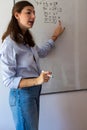 Young woman teacher explaining complex math equations on a whiteboard during an empowering education lesson, helping Royalty Free Stock Photo