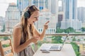 Young woman teaches a foreign language or learns a foreign language on the Internet on her balcony against the backdrop of a big