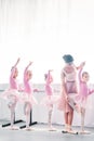 young woman teaching adorable kids dancing in ballet