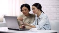 Young woman teaching grandma to use computer app, writing email, generation gap