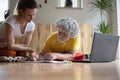 Young woman teaching a senior man how to use laptop computer