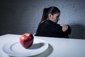 Young woman or teen with apple fruit on dish as symbol of crazy diet in nutrition disorder Royalty Free Stock Photo