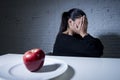 Young woman or teen with apple fruit on dish as symbol of crazy diet in nutrition disorder Royalty Free Stock Photo