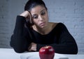 Young woman or teen looking apple fruit on dish as symbol of crazy diet in nutrition disorder Royalty Free Stock Photo