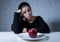 Young woman or teen looking apple fruit on dish as symbol of crazy diet in nutrition disorder Royalty Free Stock Photo