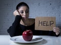 Young woman or teen looking apple fruit on dish as symbol of crazy diet in nutrition disorder Royalty Free Stock Photo