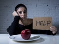 Young woman or teen looking apple fruit on dish as symbol of crazy diet in nutrition disorder Royalty Free Stock Photo