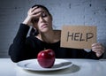 Young woman or teen looking apple fruit on dish as symbol of crazy diet in nutrition disorder