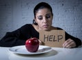 Young woman or teen looking apple fruit on dish as symbol of crazy diet in nutrition disorder Royalty Free Stock Photo