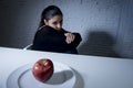 Young woman or teen looking apple fruit on dish as symbol of crazy diet in nutrition disorder Royalty Free Stock Photo