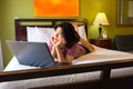 Young woman lying down on bed using laptop computer Royalty Free Stock Photo