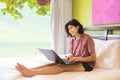 Young woman sitting up on bed using laptop computer Royalty Free Stock Photo