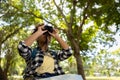 Young women teenager ethnic African American black skin wearing plaid shirt and her backpack sitting at tree base looking Royalty Free Stock Photo