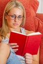 Young Woman Teenager Wearing Glasses Sitting Reading a Book at Home