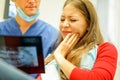 Young woman with teeth pain looking x-ray in dental clinic with her dentist - Girl ready for medical treatment - Stomatology and