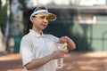 Young woman tennis player on the court drinking water. Recreation after hard exercises. Aqua balance is important Royalty Free Stock Photo