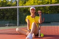 Young woman tennis player sitting on the by the net. Royalty Free Stock Photo