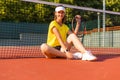 Young woman tennis player sitting on the by the net. Royalty Free Stock Photo