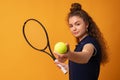 Young woman tennis player standing with racket against yellow background Royalty Free Stock Photo