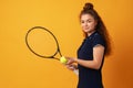 Young woman tennis player standing with racket against yellow background Royalty Free Stock Photo