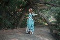 A young woman in a 19th century dress runs away along a forest path, a mystical atmosphere. Historical costume. Woman in a park or