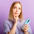 Young woman think doubt about question using smartphone. Teen girl curious dreaming, choose or decide look side on copy Royalty Free Stock Photo