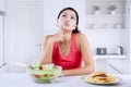 Young woman thinks to choose burger or salad