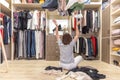 Young woman throwing clothes in walk in closet. Mess in wardrobe and dressing room Royalty Free Stock Photo