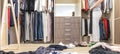 Young woman throwing clothes in walk in closet. Mess in wardrobe and dressing room