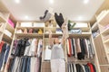 Young woman throwing clothes in walk in closet. Mess in wardrobe and dressing room Royalty Free Stock Photo