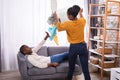 Woman Throwing Dirty Clothes On Lazy Husband