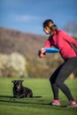 Young woman throwing freisbee to her black dog Royalty Free Stock Photo