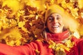 Young woman throws up orange-gold autumn leafs, view from above. Woman with yellow cap lies on the yellow and orange leaves in the Royalty Free Stock Photo